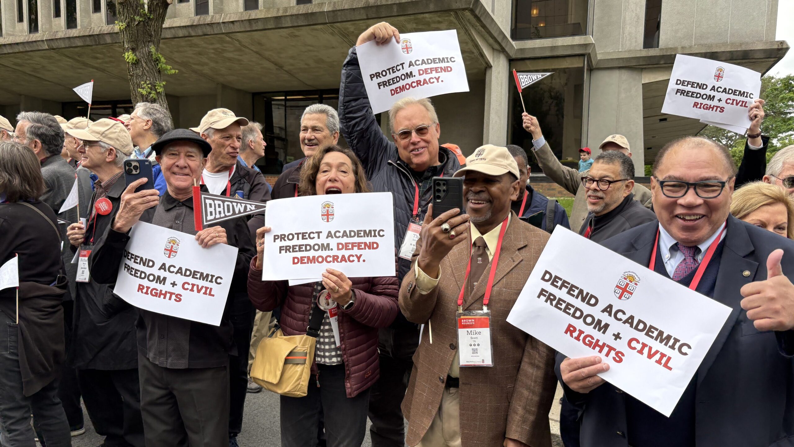 group of peiople on the street holding signs with messages about defending academic freedom